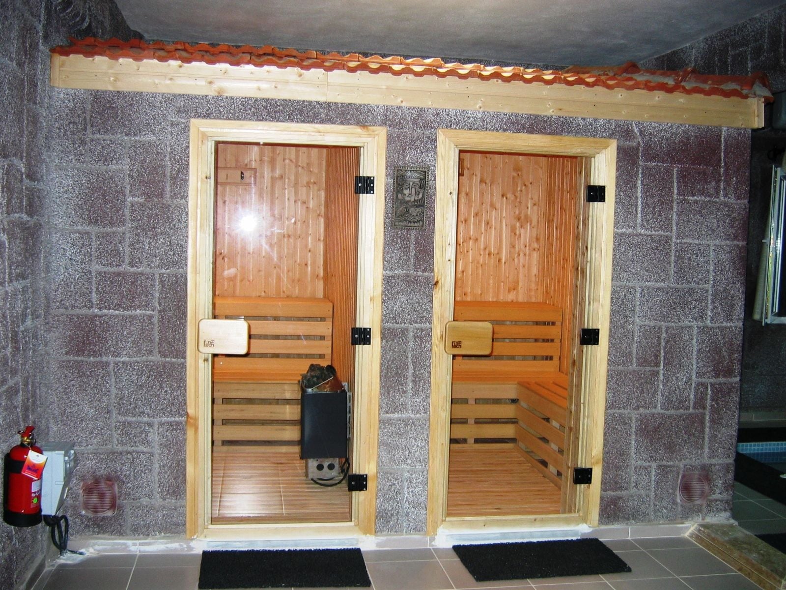 Taş kaplamalı duvarda yan yana iki ahşap sauna kabini